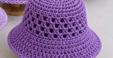 Purple crochet bucket hat with a solid crown, mesh granny square-inspired sides, and a wide, textured brim.