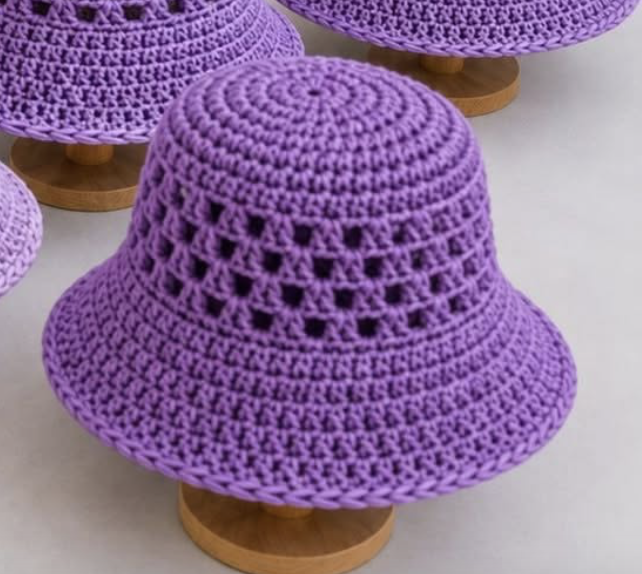 Purple crochet bucket hat with a solid crown, mesh granny square-inspired sides, and a wide, textured brim.