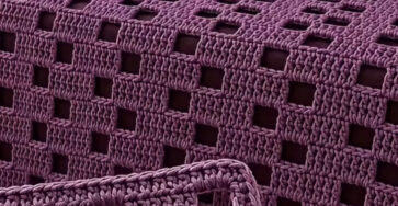 A purple crochet bedspread and pillow set with a modern open square windowpane pattern.
