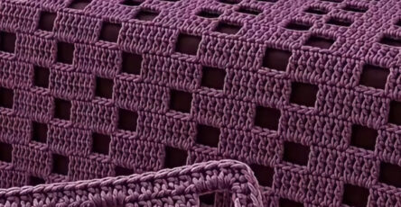 A purple crochet bedspread and pillow set with a modern open square windowpane pattern.