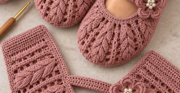 A pair of rose pink crochet Mary Jane slippers with puff stitch texture and a decorative flower with beads on the strap.