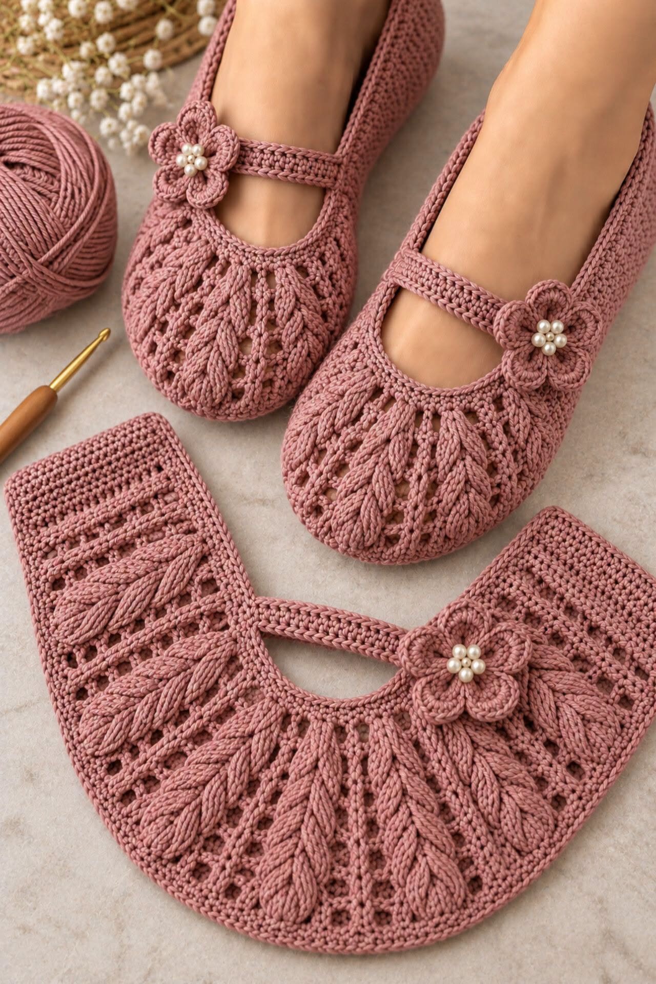 A pair of rose pink crochet Mary Jane slippers with puff stitch texture and a decorative flower with beads on the strap.