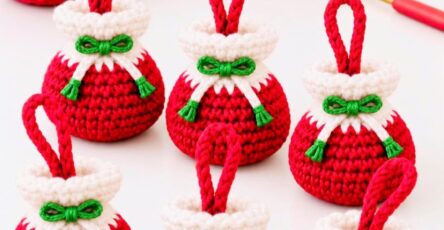 Six small crocheted Christmas gift bag ornaments in red and white with green bows, displayed with red and white yarn balls and a crochet hook.