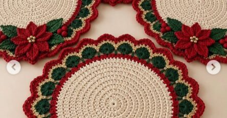 Round crochet placemat with cream center, scalloped red, green, and gold border, and a red poinsettia floral applique with green leaves.