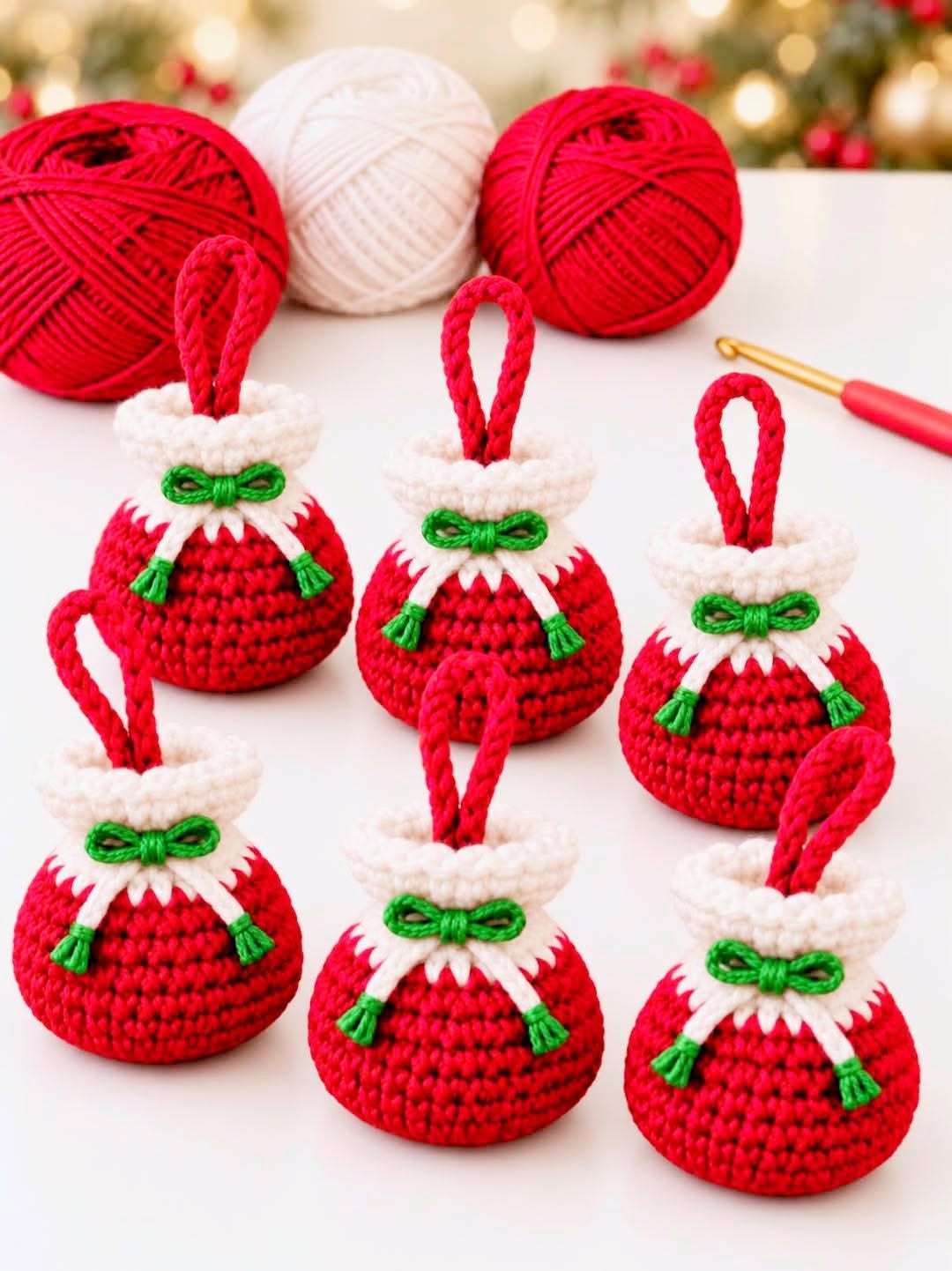 Six small crocheted Christmas gift bag ornaments in red and white with green bows, displayed with red and white yarn balls and a crochet hook.
